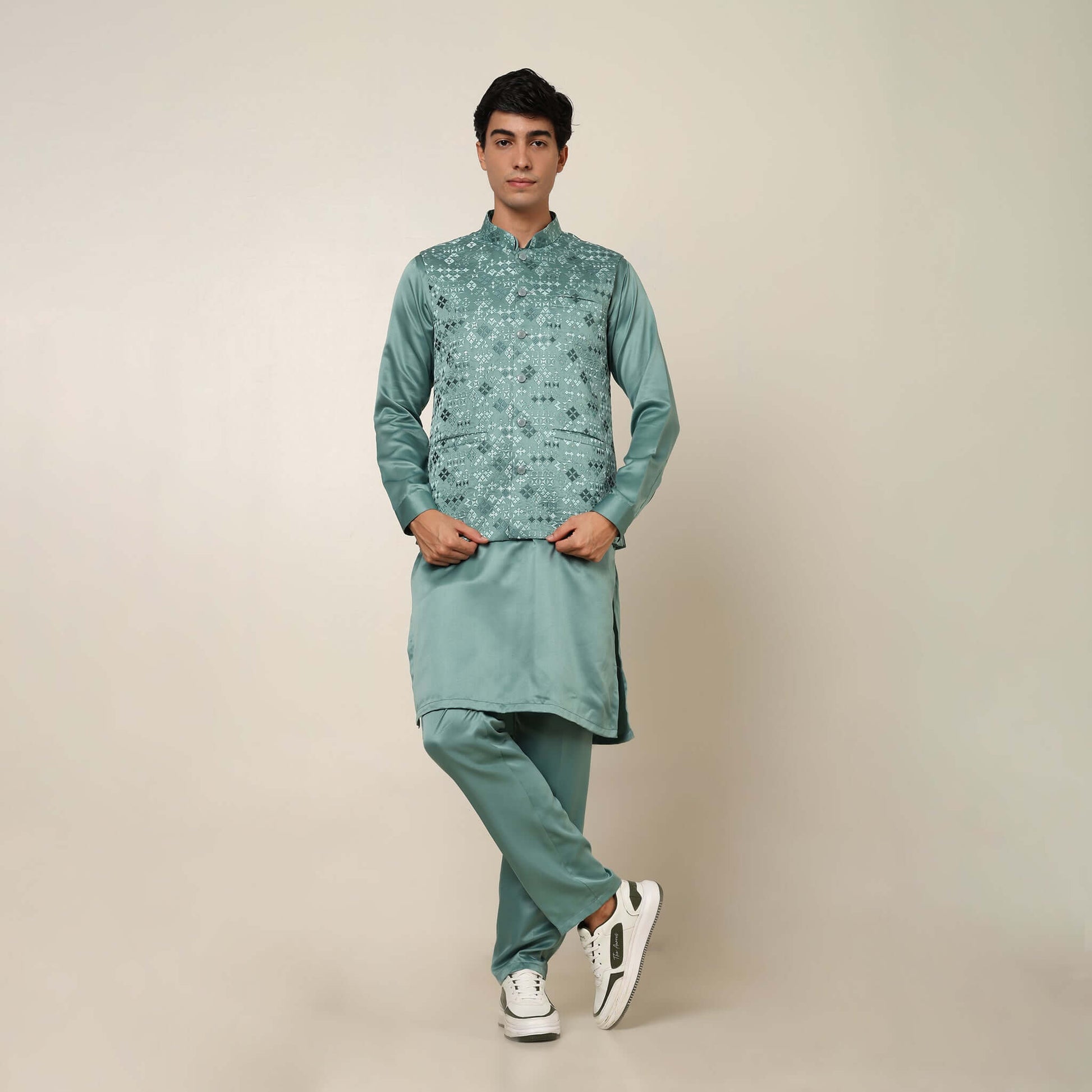 Model posing in light sea green kurta jacket set for men by Crease India, which is made up of satin & has embroidery on jacket. Ideal for groom and guests at Indian wedding reception, engagement, sangeet, anniversary and traditional festivals. Shop this m