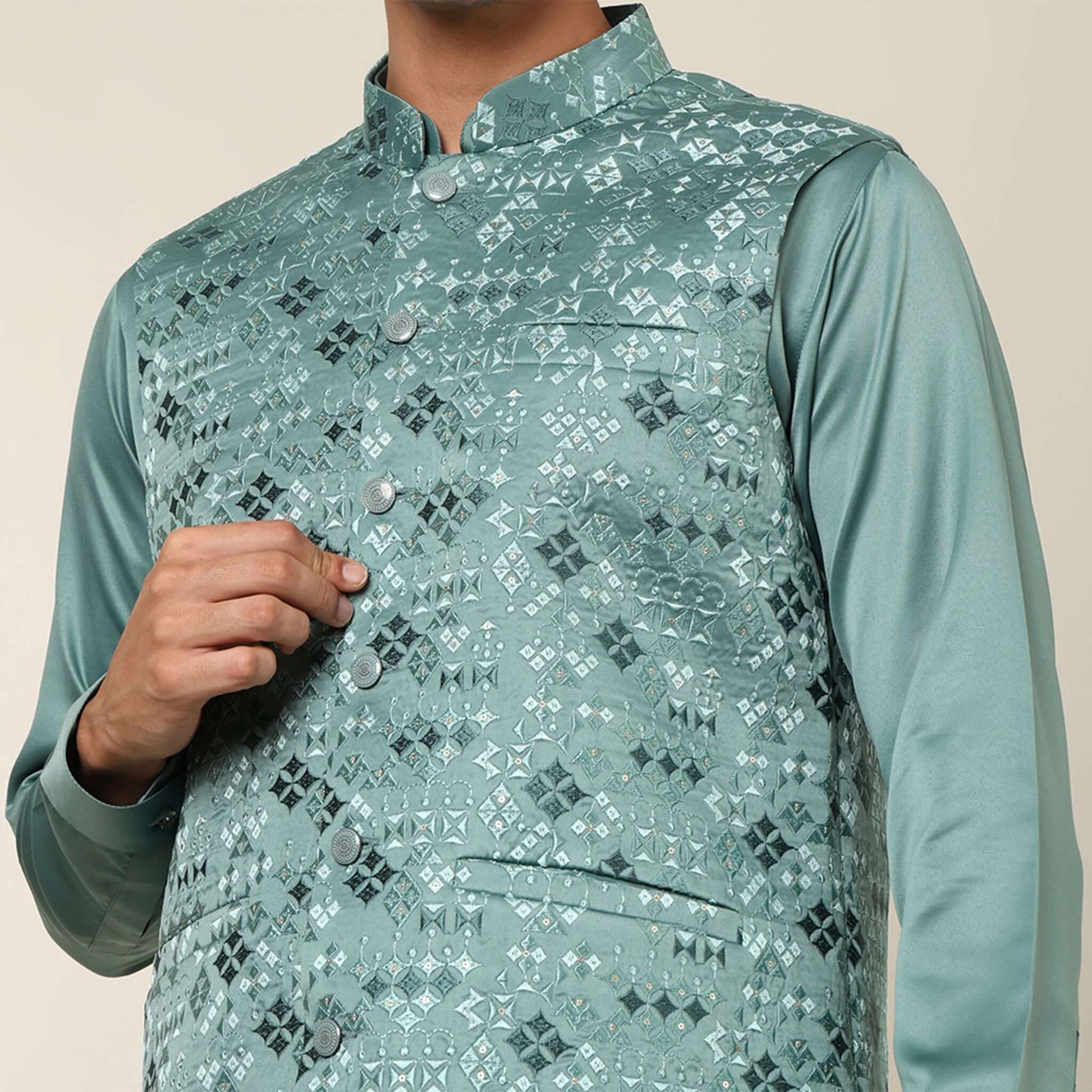 Model posing in light sea green kurta jacket set for men by Crease India, which is made up of satin & has embroidery on jacket. Ideal for groom and guests at Indian wedding reception, engagement, sangeet, anniversary and traditional festivals. Shop this m