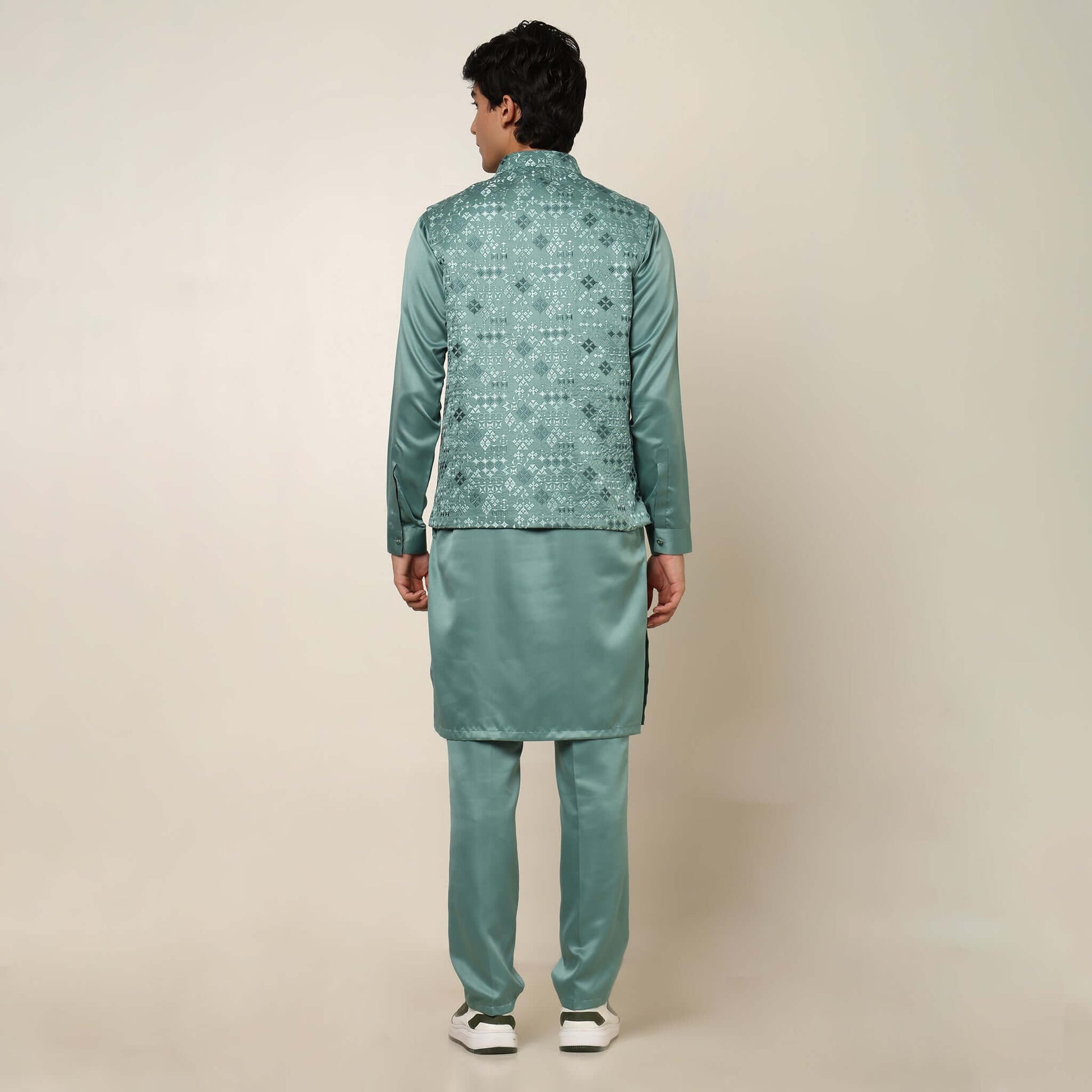 Model posing in light sea green kurta jacket set for men by Crease India, which is made up of satin & has embroidery on jacket. Ideal for groom and guests at Indian wedding reception, engagement, sangeet, anniversary and traditional festivals. Shop this m