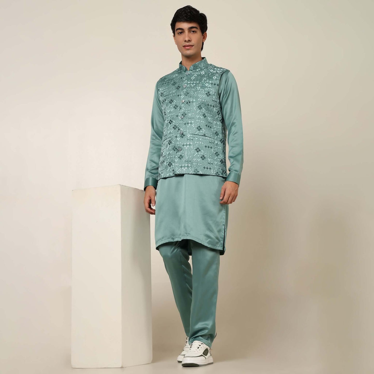 Model posing in light sea green kurta jacket set for men by Crease India, which is made up of satin & has embroidery on jacket. Ideal for groom and guests at Indian wedding reception, engagement, sangeet, anniversary and traditional festivals. Shop this m