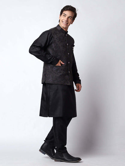 Black kurta jacket set for men available online in India. An elegant men's ethnic wear kurta jacket set with intricate black motifs design. The black jacket boasts a mandarin collar and complements the black kurta and pants, crafted from smooth dupion silk. This designer black kurta jacket set for men is ideal for weddings, Diwali, Eid, Navratri, & more festivals. Shop this designer black kurta set for men at Crease India Website.