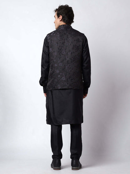 Black kurta jacket set for men available online in India. An elegant men's ethnic wear kurta jacket set with intricate black motifs design. The black jacket boasts a mandarin collar and complements the black kurta and pants, crafted from smooth dupion silk. This designer black kurta jacket set for men is ideal for weddings, Diwali, Eid, Navratri, & more festivals. Shop this designer black kurta set for men at Crease India Website.