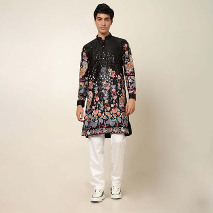 Model posing in black kurta with a tiger motif and floral embroidery by Crease India. Perfect for grooms, groom's family members, and wedding guests at sangeet, engagement, cocktail party and wedding receptions.