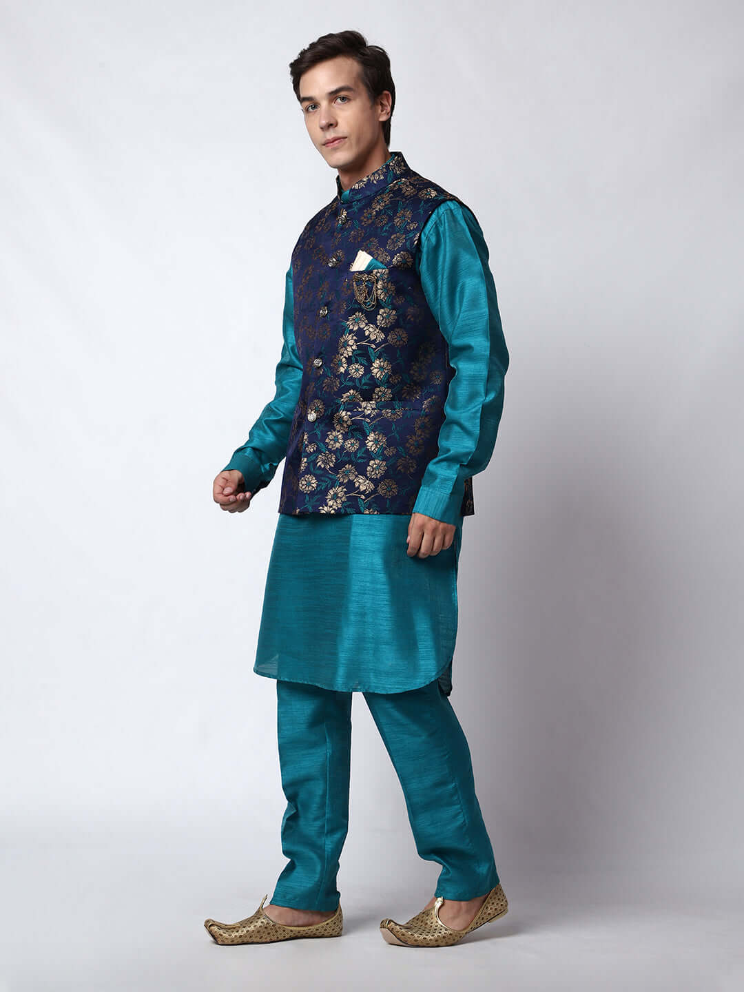 Turquoise Blue kurta jacket set for men available online in India. An elegant men's ethnic wear kurta jacket set with intricate golden floral embroidery. The sophisticated midnight blue jacket boasts a mandarin collar and complements the turquoise blue kurta and pants, crafted from smooth dupion silk. This designer kurta jacket set for men is ideal for weddings, Diwali, Eid, Navratri, & more festivals. Shop this designer kurta set for men on Crease India Website.