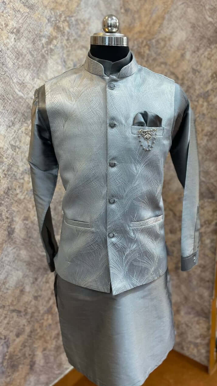 The Grey Kurta jacket set for men is available online in India. The jacket is made with a grey imported Italian jacquard fabric with abstract designs. It has a mandarin collar and goes with a matching grey hue cotton silk kurta & pants. This designer kurta set for men is perfect for weddings, parties, Diwali, Eid, Navratri & other traditional events. Shop this designer kurta jacket set for gents at the Crease India Website.