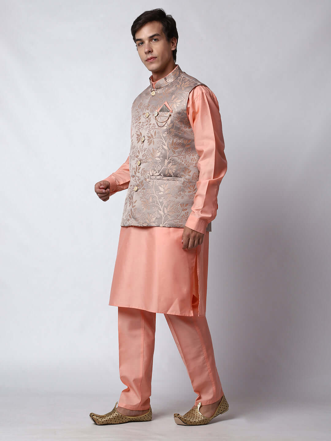 Peach kurta jacket set for men available online in India. An elegant men's ethnic wear kurta jacket set with intricate peach floral embroidery design on grey satin jacquard jacket. The grey satin jacquard jacket boasts a mandarin collar and complements the peach kurta and pants, crafted from smooth cotton silk. This designer peach satin jacquard kurta jacket set for men is ideal for weddings, Diwali, Eid, Navratri, & more festivals. Shop this designer peach kurta set for men at Crease India Website