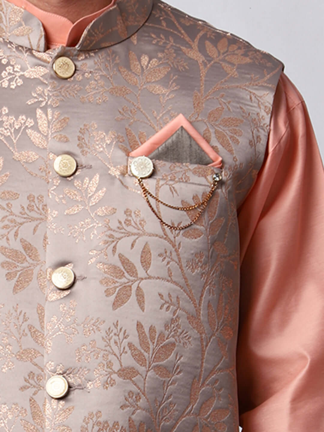 Peach kurta jacket set for men available online in India. An elegant men's ethnic wear kurta jacket set with intricate peach floral embroidery design on grey satin jacquard jacket. The grey satin jacquard jacket boasts a mandarin collar and complements the peach kurta and pants, crafted from smooth cotton silk. This designer peach satin jacquard kurta jacket set for men is ideal for weddings, Diwali, Eid, Navratri, & more festivals. Shop this designer peach kurta set for men at Crease India Website