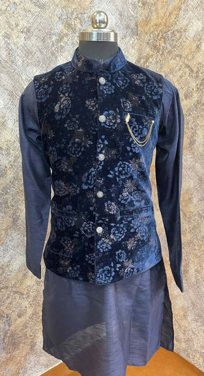 The Royal Blue Kurta jacket set for men is available online in India. The jacket is made with a velvet fabric with embossed floral patterns. It has a mandarin collar and goes with a matching blue hue dupion silk kurta & pants. This blue designer kurta set for men is perfect for weddings, parties, Diwali, Eid, Navratri & other traditional events. Shop this designer kurta jacket set for gents at the Crease India Website.